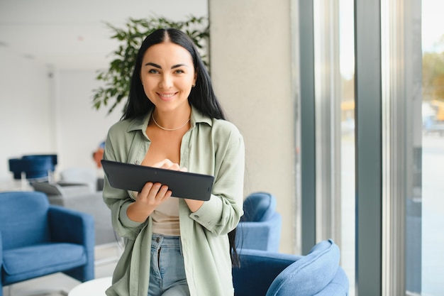 Traveler tourist woman with headphones working on laptop spreading hands during video call while waiting in lobby hall at airport Passenger traveling abroad on weekends getaway Air flight concept