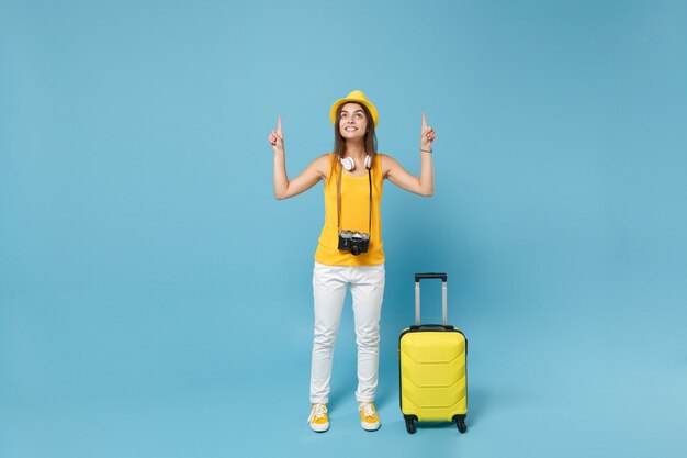 Traveler tourist woman in yellow casual clothes, hat with suitcase photo camera on blue