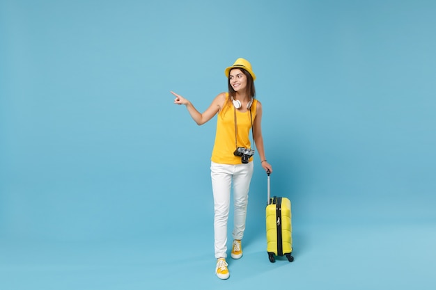 Traveler tourist woman in yellow casual clothes, hat with suitcase photo camera on blue