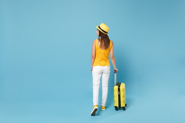 黄色のカジュアルな服を着た旅行者の観光客の女性、青いスーツケースの写真カメラと帽子