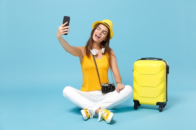 Traveler tourist woman in yellow casual clothes, hat with suitcase photo camera on blue