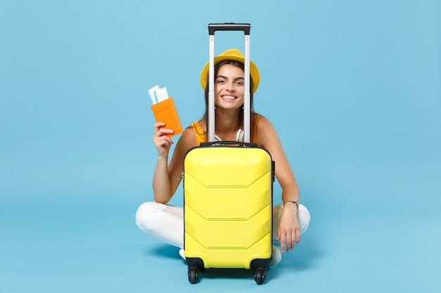 青でチケットの荷物を保持している黄色の夏のカジュアルな服の帽子の旅行者観光客の女性