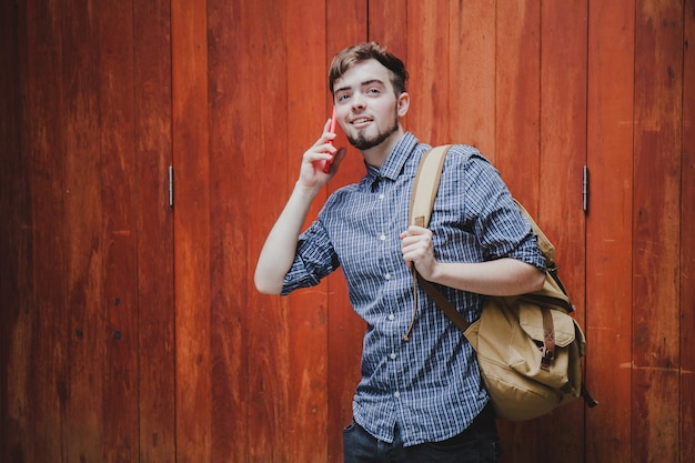 旅行者と観光の若い男がスマートフォンを使ってバックパックを着ています。旅行のバックパックのコンセプト。