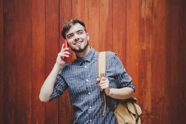 旅行者と観光の若い男がスマートフォンを使ってバックパックを着ています。旅行のバックパックのコンセプト。