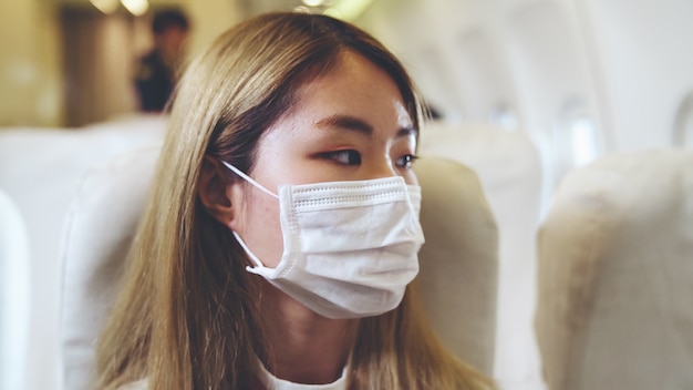 民間航空機で旅行中にフェイスマスクを着用している旅行者。