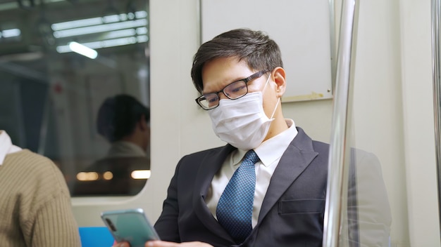 Traveler wearing face mask while using mobile phone on public train