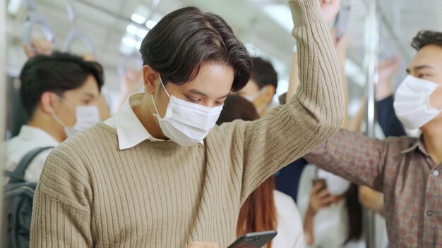 Traveler wearing face mask while using mobile phone on public train