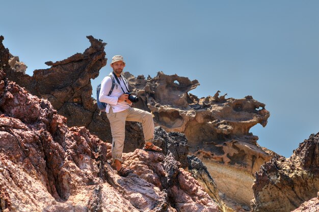 배낭과 카메라가있는 여행자는이란의 Hormuz Island, Hormuz Island의 바위에 서 있습니다.