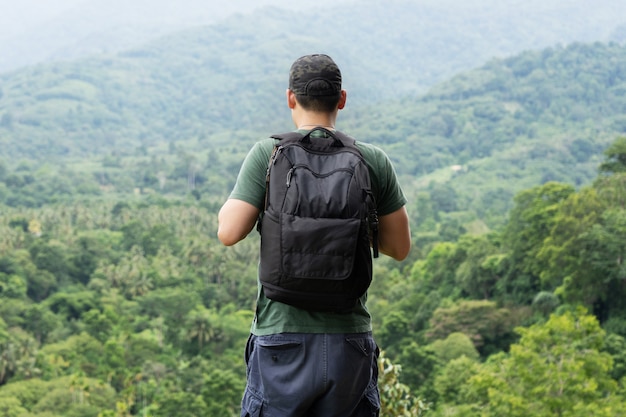 Путешественник с рюкзаком смотрит в лес
