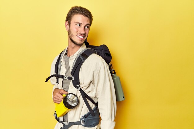 Traveler with mountain backpack and torch looks aside smiling cheerful and pleasant