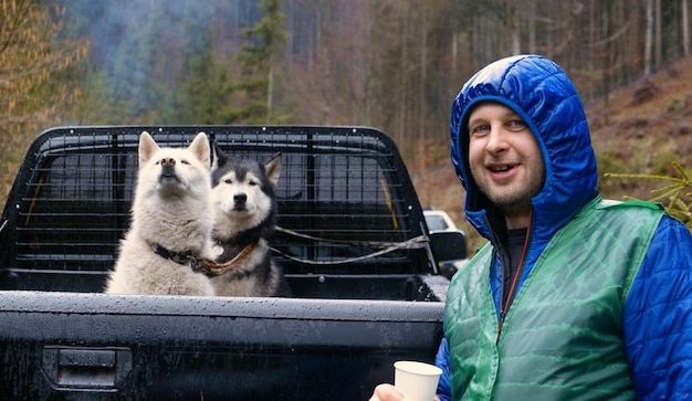 traveler with siberian tow beautiful husky dog in the wagon car person with dog in the forset