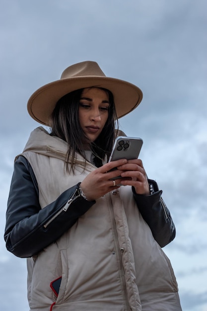 Traveler woman in hat hold in hands mobile phone Closeup smartphone technology internet online Vertical portrait of a girl tourist