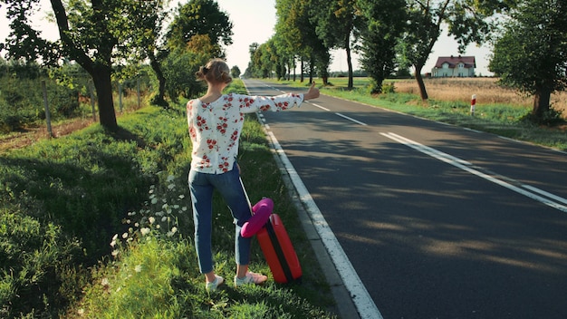 日当たりの良い道路でヒッチハイク旅行者の女性