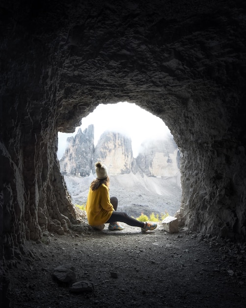 写真 旅行者の女性は、洞窟の中からイタリアのトレチーメディラヴァデロ山の景色を観察します