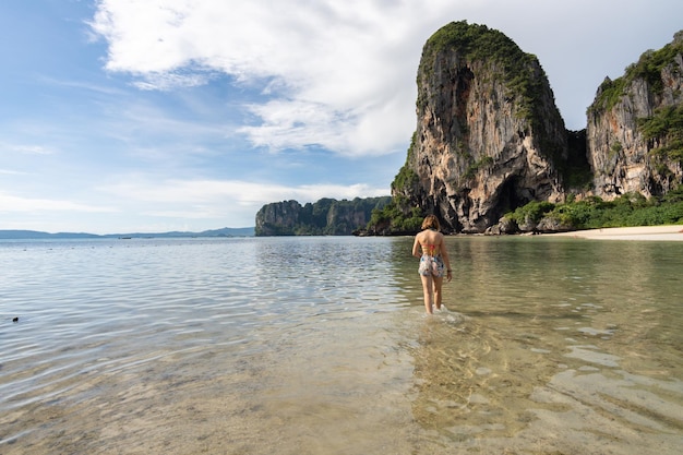 Traveler woman walking on the Phra nang Cave Beach with its turquoise waters enjoying the summer