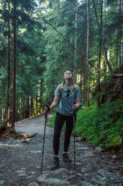 Photo traveler woman with backpack hiking through forest enjoy the beautiful sunrise on summer forest