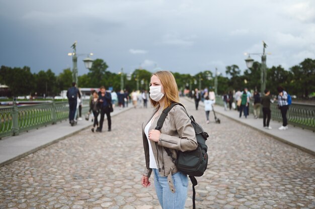 Traveler woman with a backpack and a medical mask