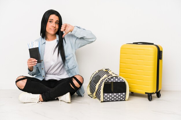 Traveler woman with her cat isolated on white wall showing a dislike gesture, thumbs down