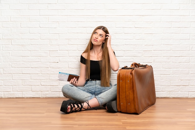 Traveler woman with suitcase and boarding pass having doubts and with confuse face expression