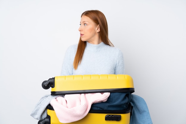 Traveler woman with a suitcase full of clothes looking side