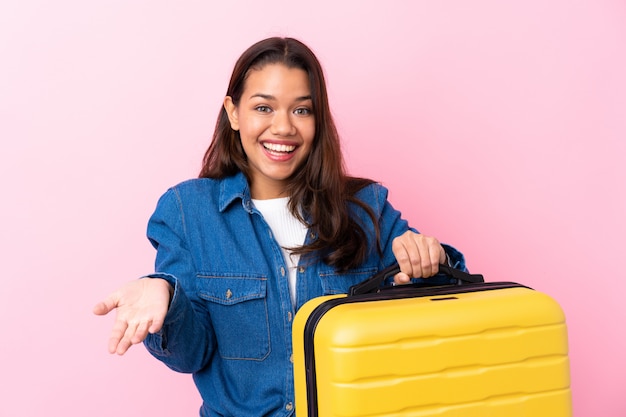 Traveler woman with suitcase over isolated wall