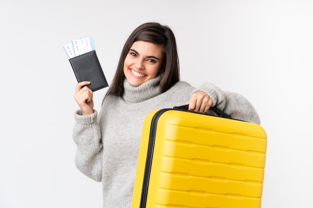 Traveler woman with a suitcase over isolated white wall