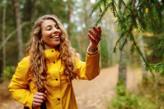 Photo traveler woman in yellow coat explores walks through wild forest in nature vacation travel concept