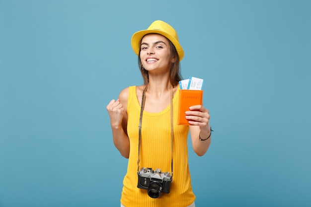 Traveler woman in yellow summer casual clothes and hat holding tickets camera on blue