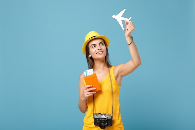 Traveler woman in yellow summer casual clothes and hat holding tickets camera on blue