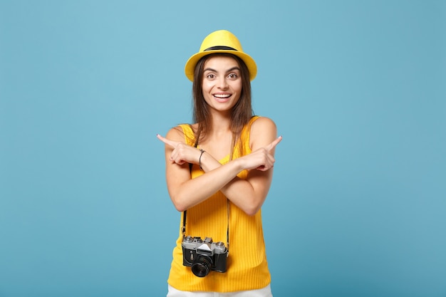 青の写真カメラと黄色の夏のカジュアルな服と帽子の旅行者の女性