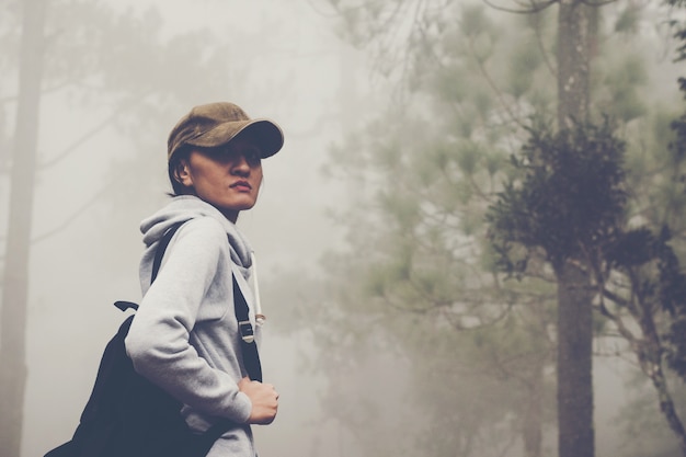 旅行者の女性は森と霧の中の森の道の道を歩いている