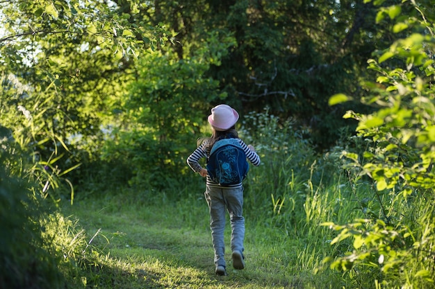 Traveler young girl with backpack walking on path in the tropical forest