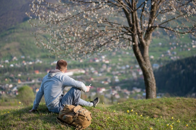 Traveler young man with backpack on hill