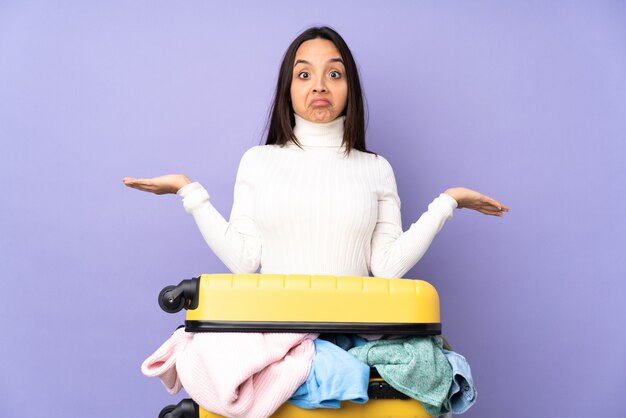 Traveler young woman with a suitcase full of clothes isolated