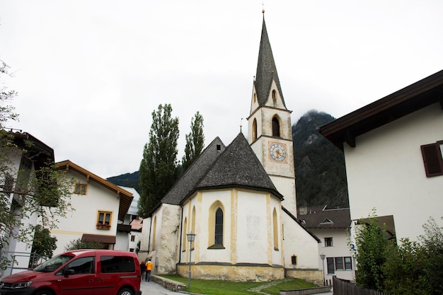 旅行者は、オーストリアのチロルの夕方にプフンツ村の小さな路地にあるルルドスカペル教会と古典的な建物を訪れます。