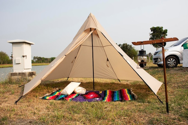 Travelers thai and foreign people travel visit and tent camping with antique lantern on grass park beside irrigation canal at Bangbuathong city rural countryside of Nonthaburi in Bangkok Thailand