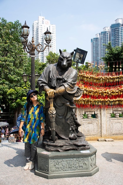 写真 2018年9月9日、中国の香港で九龍の黄大仙寺院で12の干支の犬の天使像と一緒に写真を撮るためにポーズをとっている旅行者のタイの女性
