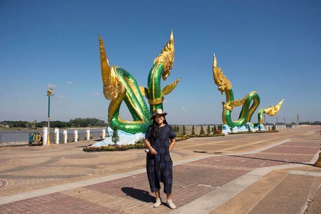 旅行者タイの女性は、タイのノンカイの川沿いのメコン川にあるランドマークとノンカイ市の視点でナーガ像と一緒に写真を撮ります