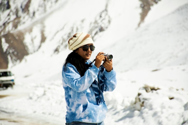 旅行者タイの女性旅行訪問スタンドは、ヒマラヤ山の頂上にあるカーダングラロードで写真を撮るために、ジャムとカシミールインドの冬のシーズン中にレーラダックのヌブラバレー村に行きます