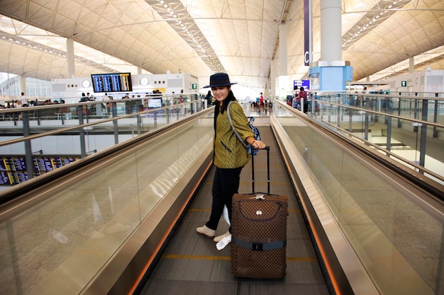 Travelers thai woman walking and drag luggage on escalator in\
terminal at chek lap kok or hong kong international airport on\
september 10 2018 in hong kong china