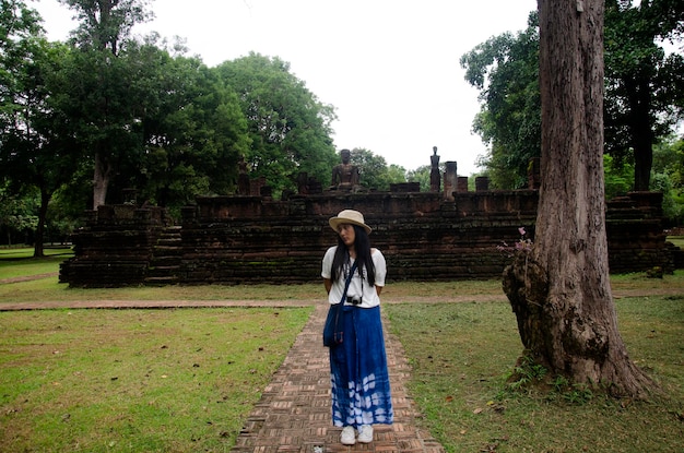 Travelers thai woman walking visit and travel take photo in ancient building and ruins of Kamphaeng Phet Historical Park is an archeological site and Aranyik Area in Kamphaeng Phet Thailand