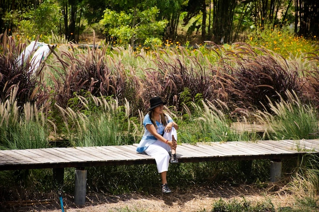 Travelers thai women people sit posing portrait on wooden bridge in garden backyard outdoor and travel visit rest relax in flower grassland with wind and mountain background in Kanchanaburi Thailand