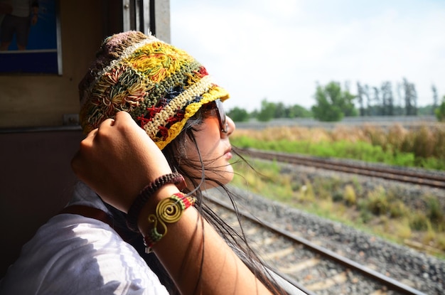 여행 탐험가와 기차에서 포즈를 취하는 초상화를 위해 철도에 앉아 있는 여행자 태국 여성
