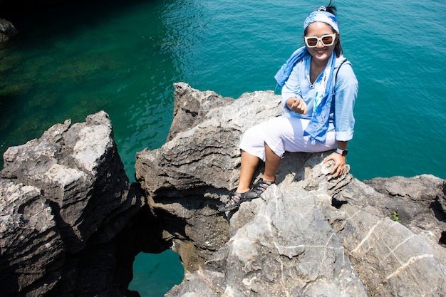 Travelers thai women people travel visit unseen trip at ao toa\
ba beach and posing portrail take photo with stone sea heart on\
cliff in ocean of pak bara waterfront at la ngu city of satun\
thailand
