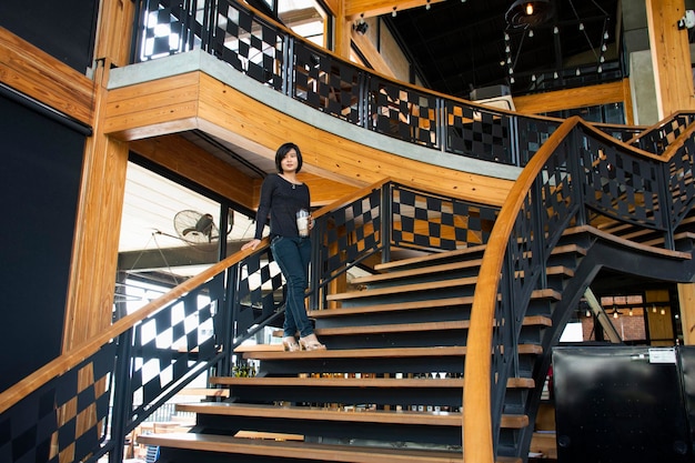 Travelers thai women walking up on classic wooden stairs in modern and luxury restaurant in Bangkok Thailand