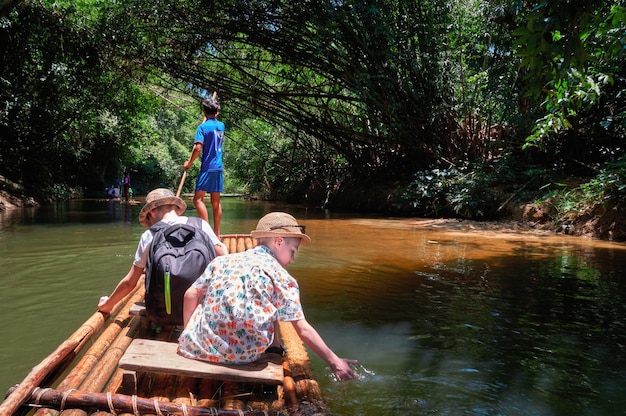 Traveling on bamboo rafts on tropical river with children