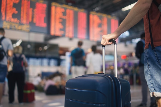 traveling by airplane man waiting in airport terminal selective focus on hand holding suitcase