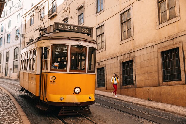 Photo traveling by portugal happy young woman walking by streets in lisbon famous yellow tram