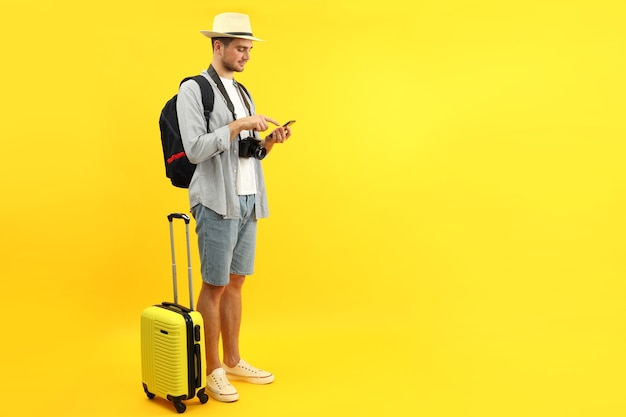 Traveling concept with young man on yellow background, space for text.