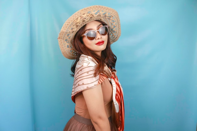 Traveling concept of a young Asian happy woman isolated by a blue background